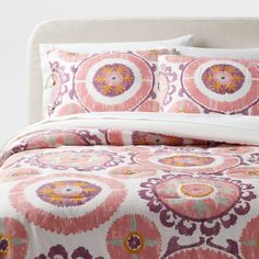 a bed with pink and orange bedspread, pillows and comforter on it