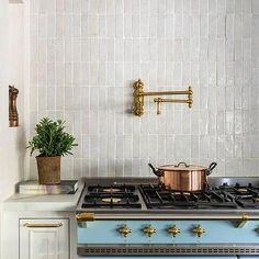 a stove top oven sitting inside of a kitchen next to a pot filled with plants