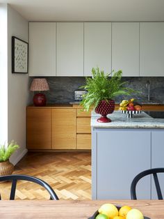 a bowl of fruit sitting on top of a wooden table next to a kitchen counter