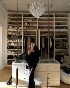 a woman standing in front of a closet filled with clothes