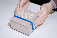 a person holding a box with the word age printed on it, while another hand reaches out