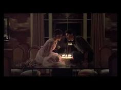 a bride and groom sitting in front of a cake with lit candles on it at night