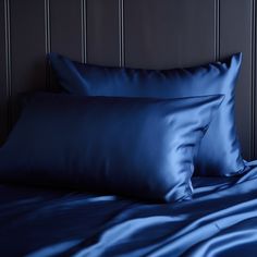 two blue pillows sitting on top of a bed