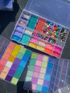 two plastic containers filled with lots of different colored beads next to each other on a table