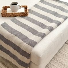 a cup of coffee sitting on top of a bed next to a tray with a blanket