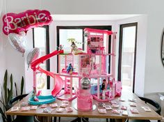 a barbie doll house is set up on a table in front of a large balloon