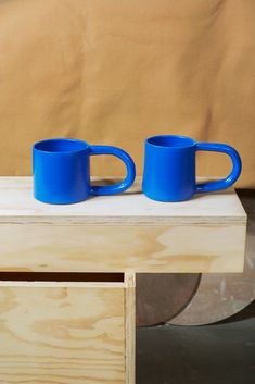 two blue mugs sitting on top of a wooden table