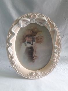 an old fashioned photo frame with two young children in white dresses and bows on it