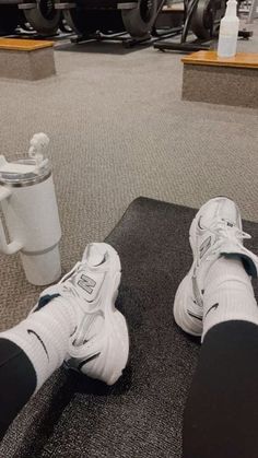 someone's feet resting on a mat in front of a coffee cup and car