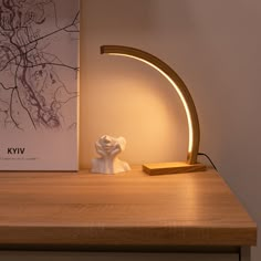 a white lamp sitting on top of a wooden table next to a book and a light