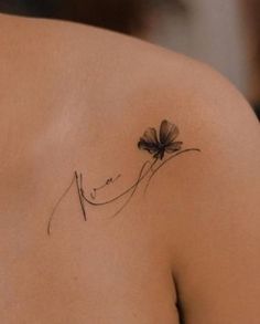 a woman's shoulder with a single flower tattoo on her left shoulder and the word love written in cursive writing