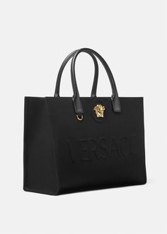 Crafted in tonal canvas with leather top handles, this classic tote bag is adorned with a Medusa plaque and raised Versace logo lettering. The roomy interior has a large zipped pocket and protector strap. Attach a Versace bag charm with the D-ring for an added touch of style. Versace Bag, Womens Designer Bags, Versace Bags, Tote Bag Pattern, Large Tote Bag, Leather Items, Black Tote Bag, Canvas Tote Bag, Large Tote