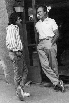 two men standing in front of a door talking to each other while another man looks on