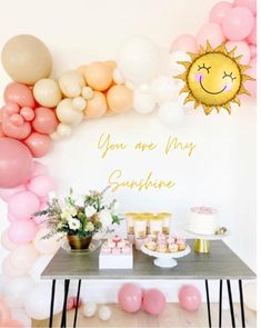 a table topped with lots of balloons next to a sign that says you are my sunshine