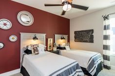 two beds in a room with red walls and black and white decor on the wall