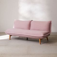 a pink couch sitting on top of a wooden floor