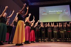 a group of people standing on top of a stage with their hands in the air