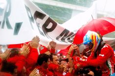 a group of people in red shirts and helmets holding umbrellas