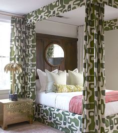 a bedroom with green and white curtains on the windowsills, a bed in front of a mirror