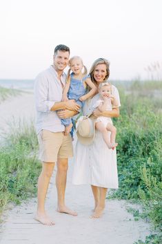 a family poses for a photo on the beach in front of tall grass and sand dunes