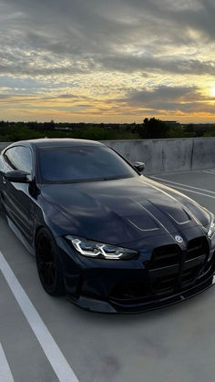 a black sports car parked in a parking lot with the sun shining down on it