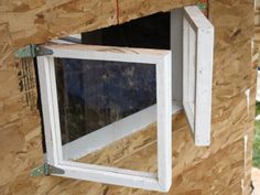 an open window on the side of a building being built with plywood and wood