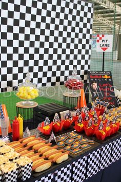 a table topped with lots of hot dogs and buns next to other food items