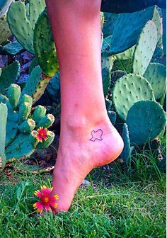 a person's foot with a small tattoo on it and cactus in the background