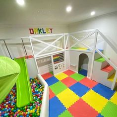 an indoor play area with lots of colorful balls and plastic blocks on the floor, including a slide