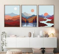 three paintings are hanging on the wall above a white cabinet in a modern living room