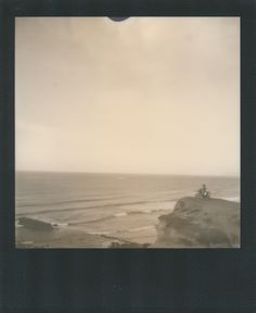 two people sitting on top of a rock near the ocean