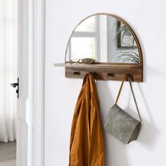 a mirror and coat rack hanging on the wall next to a window with a potted plant in it