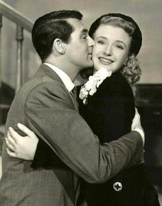 an old photo of a man kissing a woman on the cheek in front of stairs