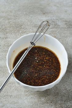 a white bowl filled with spices and whisk on top of a countertop