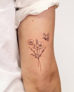 a small flower tattoo on the side of a woman's right leg, with two butterflies flying over it