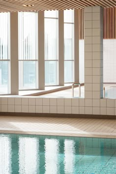 an indoor swimming pool with tiled walls and windows