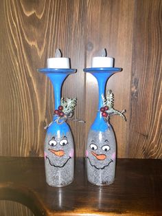 two blue vases with faces painted on them sitting on a wooden table next to each other