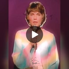 an old photo of a woman holding a microphone in front of her face and wearing a tie dye shirt