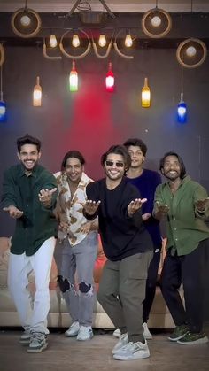 group of men standing in front of a couch posing for the camera with their hands up