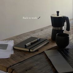 an open laptop computer sitting on top of a wooden table next to a coffee maker