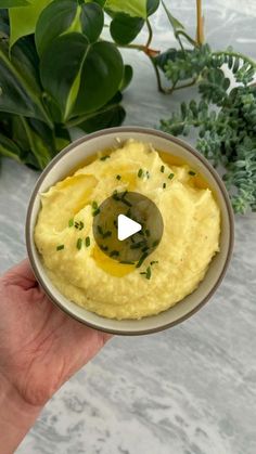 a hand holding a bowl filled with mashed potatoes