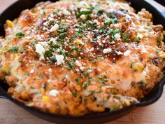 a casserole with cheese and vegetables in a black pan on a wooden table