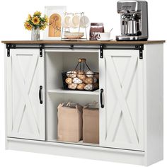 a white cabinet with two open doors and baskets on the bottom, next to a coffee maker