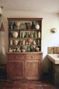 a wooden cabinet filled with lots of vases and bowls on top of it's sides