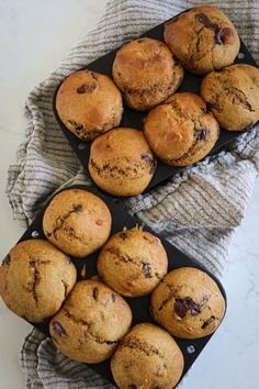 chocolate chip muffins on a black tray next to a gray and white towel