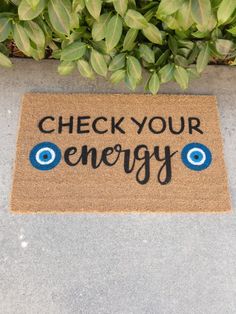 a door mat with the words check your energy written on it next to some plants