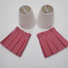 two lamps with red and white striped pleated shades next to each other on a white surface