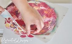 a person is using a paintbrush to decorate a flower design on a paper plate