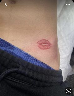 a woman's stomach with a red lip tattoo on the side of her stomach