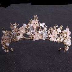 a tiara with flowers and pearls is shown on a black surface in this image